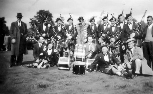 Bandsmen sitting on the grass, perhaps in the Christie Park